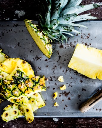Ananas geschält und in Stücke geschnitten auf grauem Untergrund