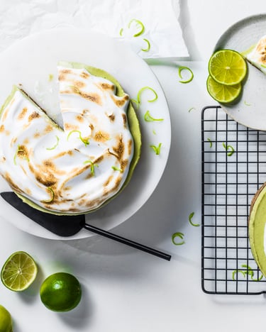 Angeschnittener Key Lime Pie mit flambierter Baiserhaube vor hellem Hintergrund