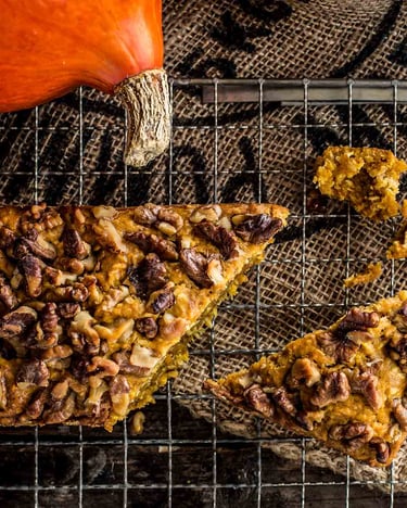 Angeschnittener Kürbis-Kuchen mit Pekannüssen  aus Kastenform auf Holzuntergrund