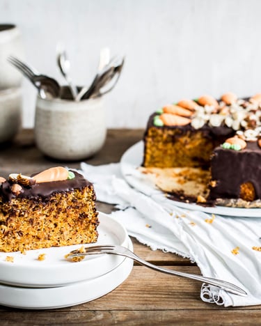 Angeschnittener runder Möhrenkuchen mit Schokolade auf Holztisch
