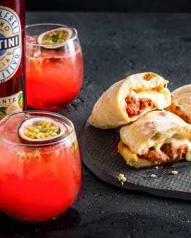 3 Mini-Calzoni liegen auf schwarzem Untergrund, daneben Martini