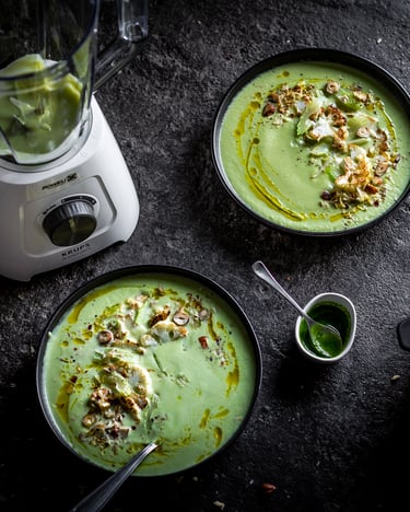 Blumenkohl-Sellerie-Suppe in zwei dunklen Schüsseln, getoppt mit Haselnüssen, daneben noch der Topf mit Suppe, fotografiert von oben auf dunklem Untergrund, neben dem KRUPS Blendforce 2-in-1.
