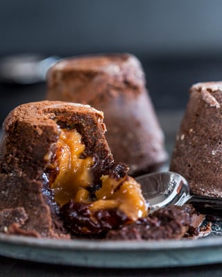 Drei kleine Lava Cakes, von denen einer angeschnitten ist, sodass der Karamellkern im Inneren sichtbar wird