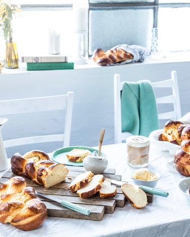 Unterschiedliche Hefezöpfe für Ostern auf dem weiß gedeckten Tisch.