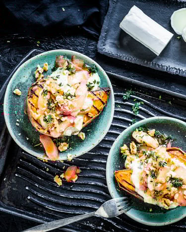 Grilled Sweet Potato mit Ziegenkäse-Honig-Creme auf türkisen Tellern, von oben fotografiert, daneben eine gereifte Ziegenkäserolle auf separatem Teller.