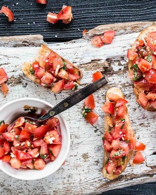 Bruschetta mit Tomaten belegt auf Holzbrett mit dunklem Hintergrund