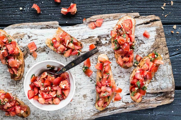 Bruschetta mit Tomaten belegt auf Holzbrett mit dunklem Hintergrund