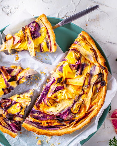 Quiche mit Wurzelgemüse und bunten Möhren von oben auf weißem Untergrund