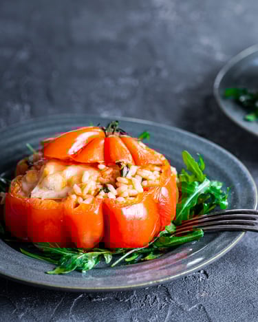 Pomodori ripieni auf Salatbett auf dunklem Teller vor dunklem Hintergrund