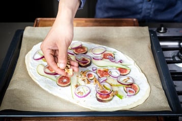 Der Flammkuchen wird belegt