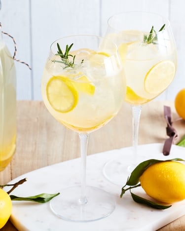 2 Gläser alkoholfreier Limoncello Spritz, daneben Zitronen