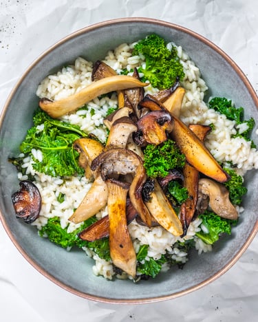 In einer weißen Schale liegt Risotto mit Pilzen und Kohl