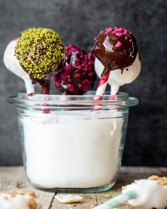 Bunt verzierte Cake Pops im Schokoladenmantel  in Glas gesteckt auf Holz