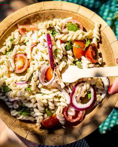 Nudelsalat auf einem Teller in der Hand