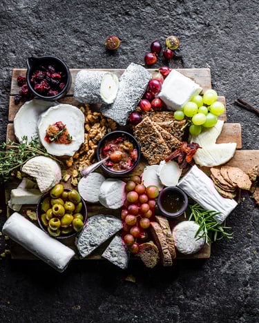 Ziegenkäseplatte, belegt mit dem leckersten Ziegenkäse aus Frankreich und jeder Menge anderer Leckereien auf dunklem Steinuntergrund von oben fotografiert.
