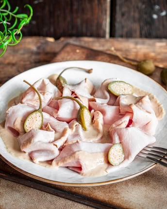 Vitello Tonnato auf weißem Porzellanteller mit dunklem Holzhintergrund