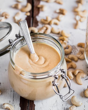 Selbstgemachtes Cashewmus in Einmachglas vor hellem Hintergrund.