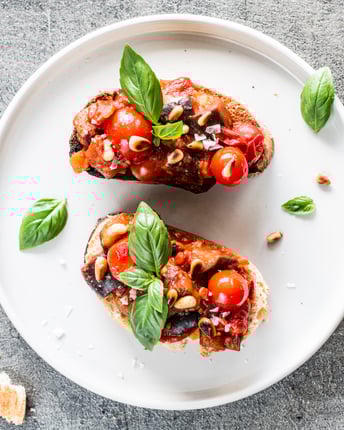 Zwei Crostini mit Caponata auf einem weißen Teller