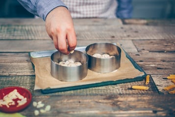 Semifreddo, in zwei Ausstechformen aufgeteilt, die auf einem kleinen Backblech stehen, werden mit Mandeln bestreut