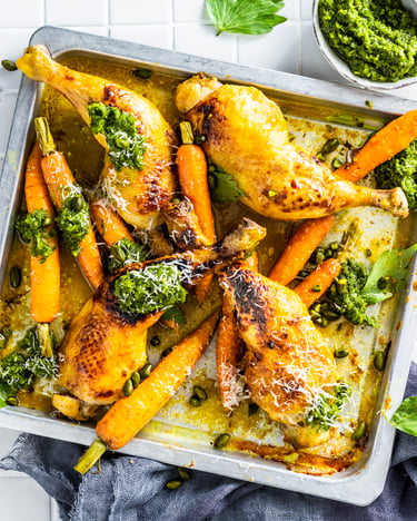 Hähnchenschenkel und gebackene Möhren mit Pesto in einem Backblech
