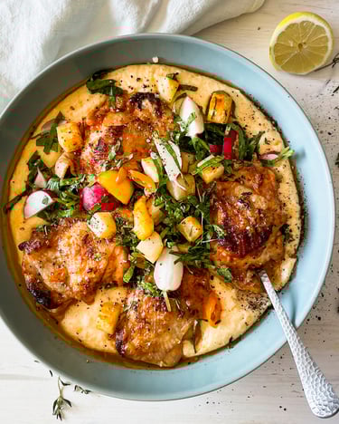 Hähnchen auf Polenta in türkiser Schüssel, darin liegt ein Löffel