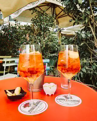 Zwei Gläser Aperol Spritz auf einem Tisch mit orangefarbiger Tischdecke