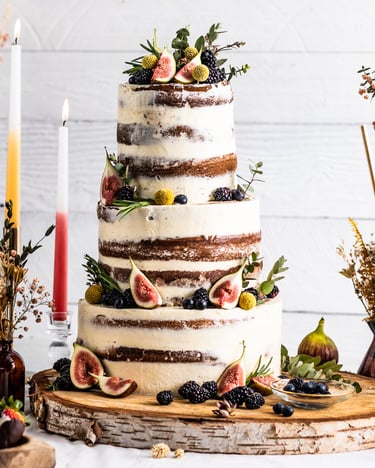Mittig steht eine dreistöckige Hochzeitstorte auf einem natürlich dekorierten Tisch