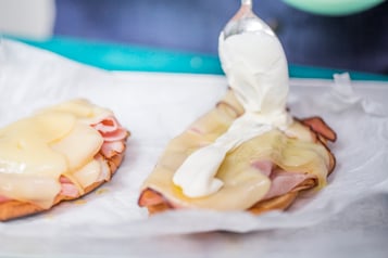 Auf das Brot wird mit einem Löffel Creme Fraiche gegeben.
