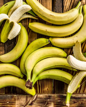 Viele Bananen, teilweise geschält und ungeschält, vor Holzuntergrund