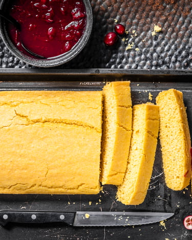Gelbes Maisbrot auf schwarzem Tablett, dazu Cranberry-Sauce.