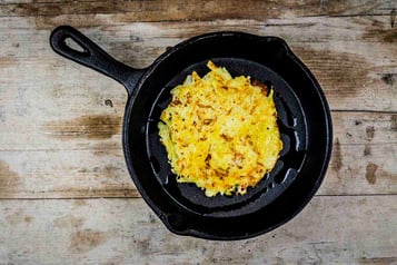 In einer schwarzen Pfanne befindet sich ein Rösti