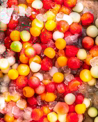 Close-up von ausgestochenen Melonenkugeln, die mit Eiswürfeln gekühlt werden