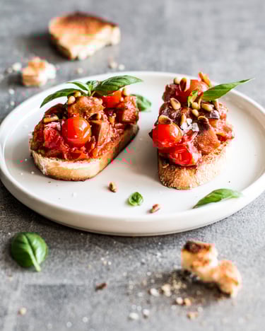 Zwei Crostini mit Caponata auf einem weißen Teller