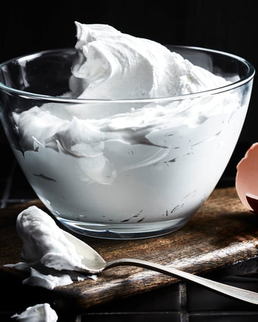 In einer Schale befindet sich Icing, daneben ein aufgeschlagenes Ei
