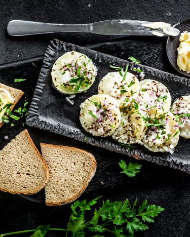 Harzer Käse auf dunklem Untergrund mit Brotscheiben und Butter