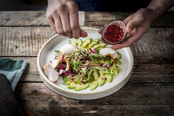 Über das Avocado-Carpaccio werden Granatapfelkerne gestreut