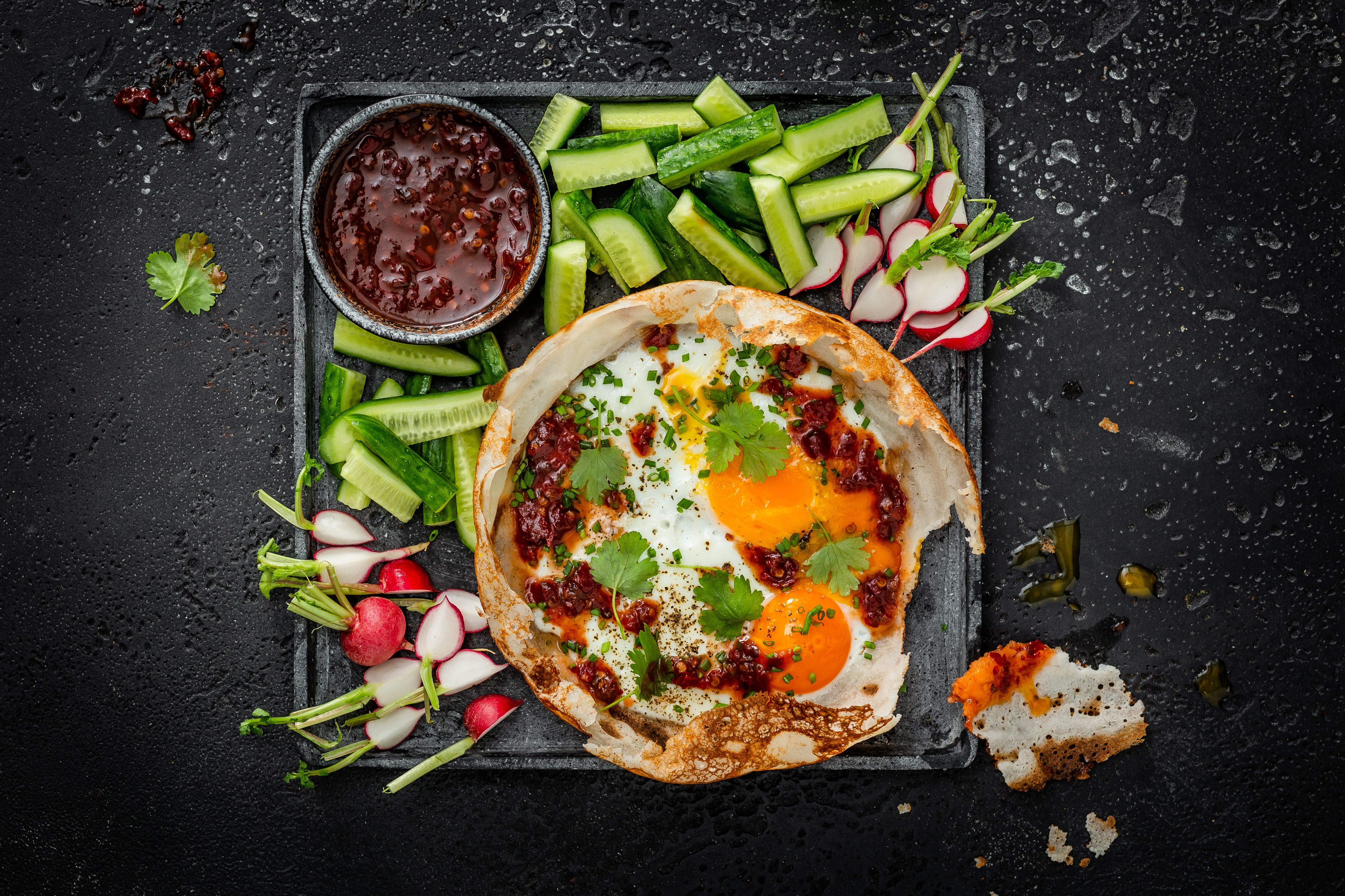 Ein Tablett mit Egg Hoppers (Spiegelei imPfannkuchen) mit Gurken, Radieschen und einem Soja-Dip