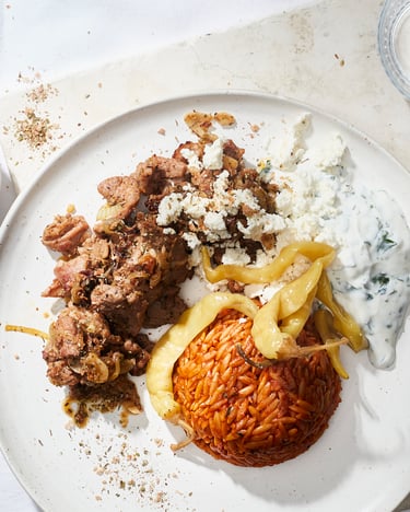 Kritharaki-Nudeln neben Gyros und Joghurtsauce auf einem weißen Teller