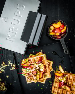 Haselnusswaffeln mit Pflaumenkompott aus dem Krups Waffeleisen, fotografiert von oben auf dunklem Untergrund.