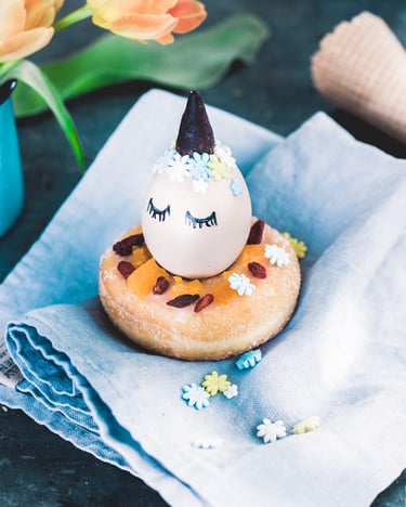 verziertes Ei mit Horn und Wimpern in Zuckerdonut gesetzt