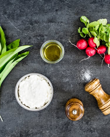 Fünf Zutaten zum Kochen: Bärlauch, Hüttenkäse, Öl, Radieschen und Gewürze.