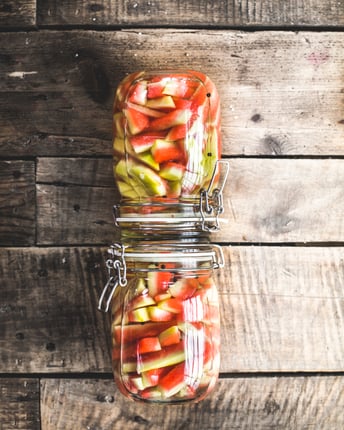 Gepickelte Wassermelonenschalen in zwei Einmachgläsern vor Holzhintergrund