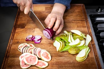 Eine rote Zwiebel wird auf einem Schneibrett in Ringe geschnitten