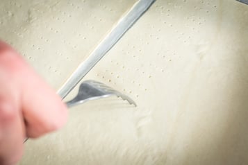 In einen Teig wird mit einer Gabel mehrmals eingepikst