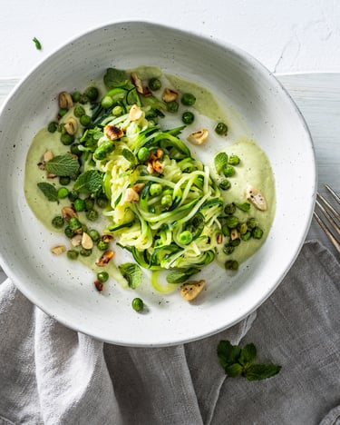 Zucchininudeln mit Cashew-Sauce auf weißem Untergrund