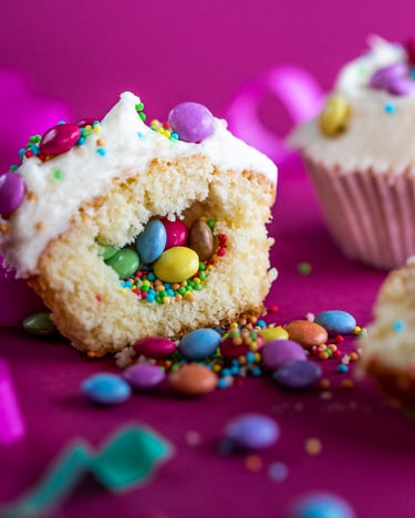 Cupcakes mit Smarties-Füllung auf pinkem Untergrund