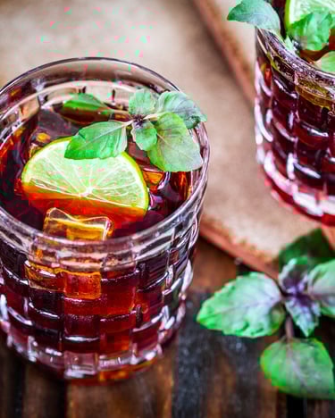 2 Gläser Averna Red Basil auf einem Holztisch