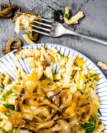 Auf dunkelgrauem Untergrund ein Teller mit Käsespätzle