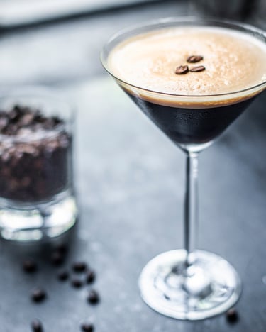 Espresso Martini auf dunklem Untergrund und Glas mit Kaffeebohnen im Hintergrund