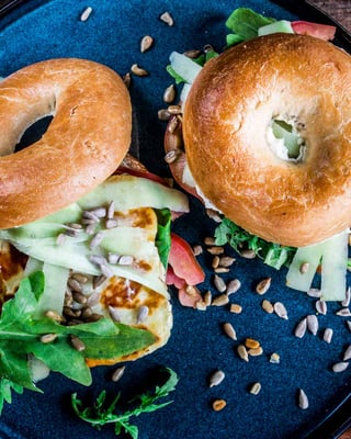 2 Bagel liegen auf einem schwarzen Teller. Als Deko: Sonnenblumenkerne